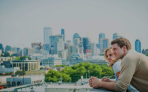 Uptown 11 Apartments Seattle WA | Man & Woman Looking Out Balcony at City Skyline